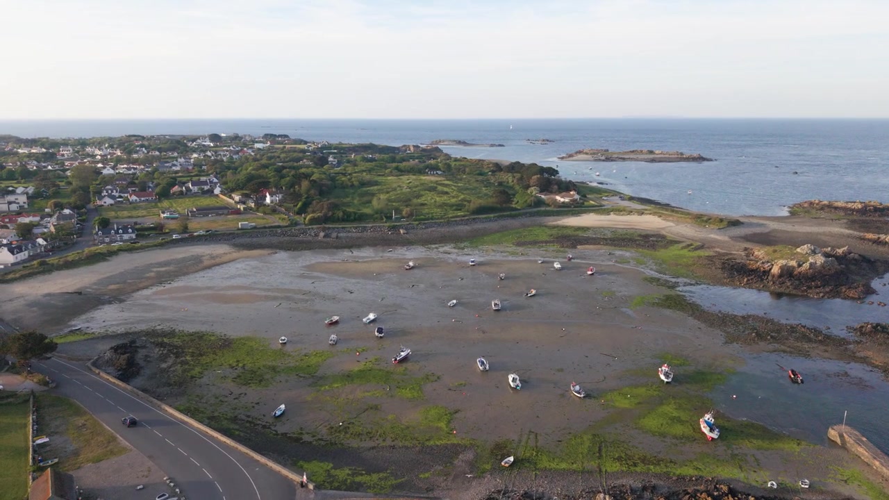 Porto di Bordeaux, Guernsey, Isole del Canale. Riprese aeree con drone in avanti direttamente sopra il vecchio porto con piccole imbarcazioni che si asciugano sulla costa orientale con la bassa marea, acqua calma e viste lontane