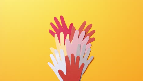 cerca de las manos juntas hechas de papel de colores sobre fondo amarillo con espacio para copiar