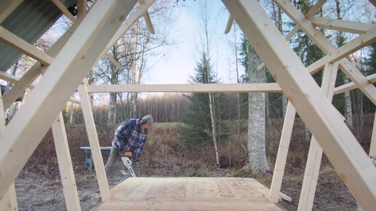 Female carpenter use petrol chainsaw to cut timber during tiny house build