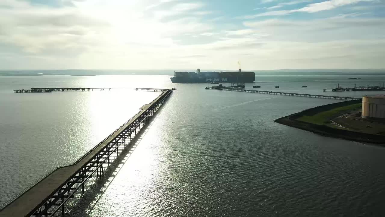 Aerial : Drone lifts flying backwards with huge ship, pier walkway, industrial refinery in view.  Mavic 2 Pro HD60fps