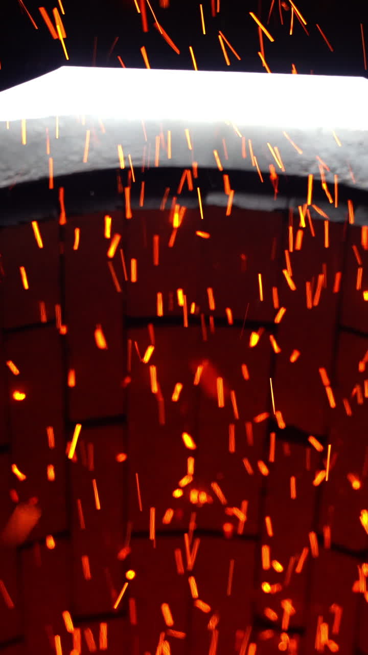 Fast shining sparkles flying quickly from their source. Bright ablaze particles at the brick backdrop. Close up. Vertical video