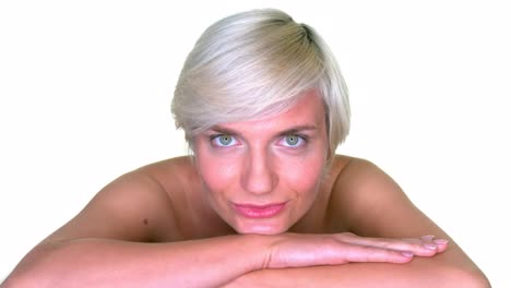 a woman resting her chin on her crossed arms, smiling at the camera on a seamless white studio background