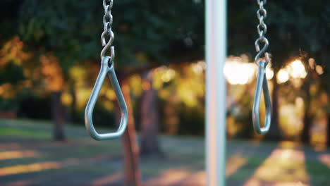 gymnastic steel rings on chain at outdoor gym in park backlit with sunlight