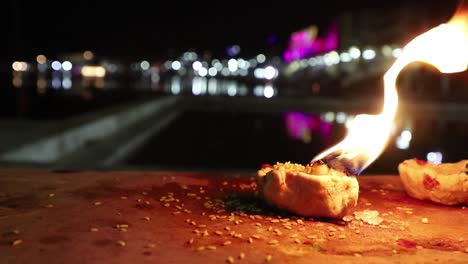 Lámparas-De-Aceite-Encendidas-Después-De-Puja-Con-Pushkar-Ghat-En-El-Fondo,-Noche,-Lugar-Espiritual