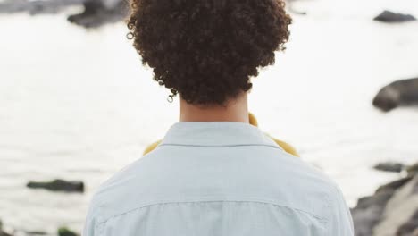 vista trasera de una pareja afroamericana abrazándose en las rocas cerca del mar