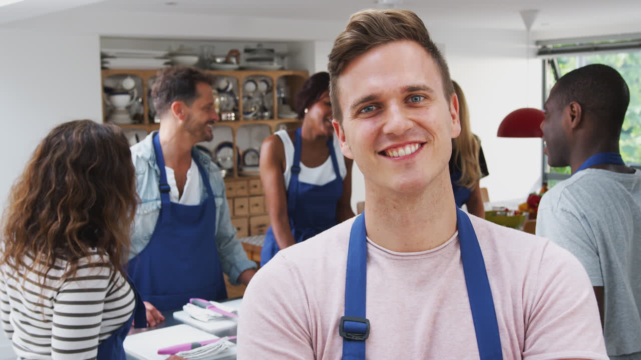 retrato de homem sorridente vestindo um avental participando de uma aula de culinária na cozinha