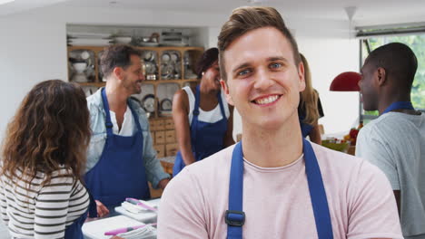 Portrait-Of-Smiling-Man-Wearing-Apron-Taking-Part-In-Cookery-Class-In-Kitchen