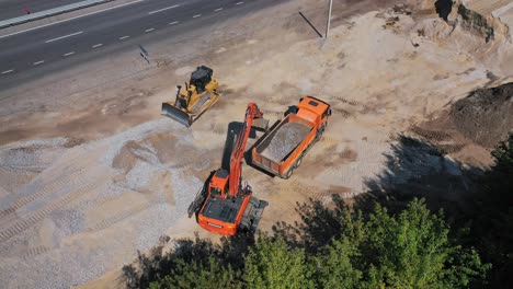 excavator pours sand into the truck. aerial view of excavator with truck working in quarries site