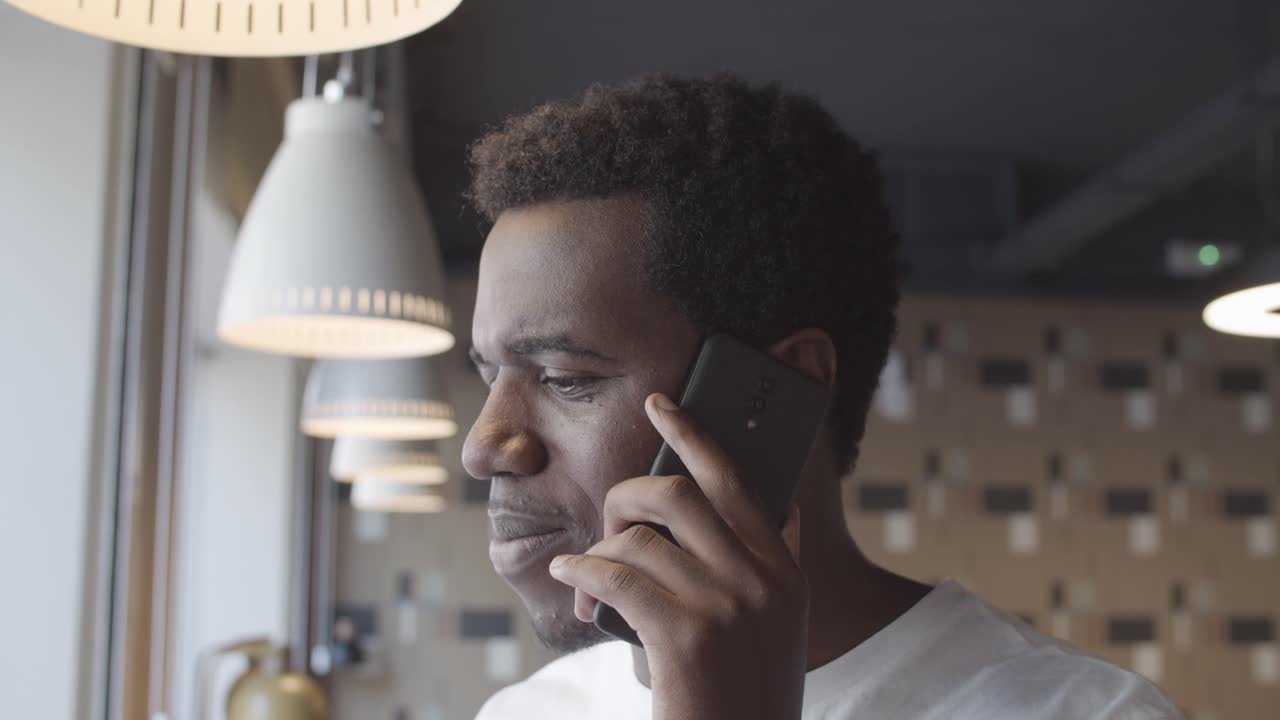 Cheerful young African American man talking on mobile phone