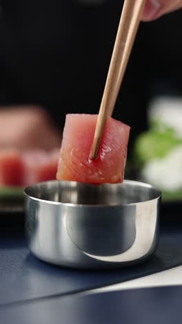 preparando un pedazo de sashimi de atún con palillos