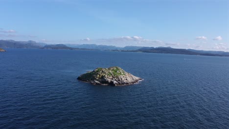 a small rocky island in the ocean, surrounded by clear blue waters in norway, aerial view