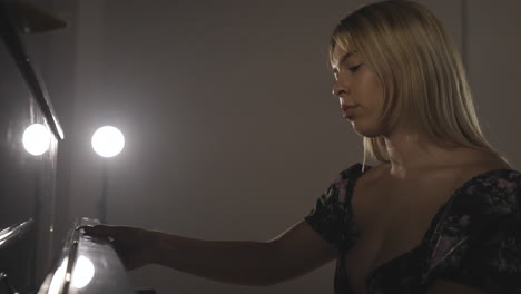 female pianist sits down by the piano, opens the fallboard, ready to play