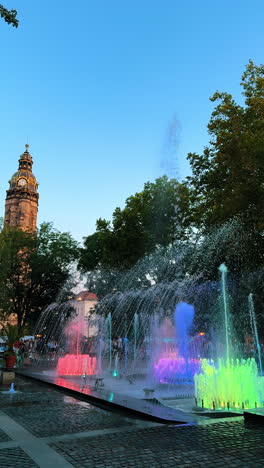 dancing fountains and light show. an old tower top at backdrop. kosice, slovakia. vertical video.