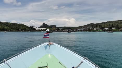 el ferry tailandés con bandera ondulante se acerca al muelle de koh phi phi, tailandia