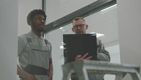 two engineers discussing work with a laptop in a modern factory