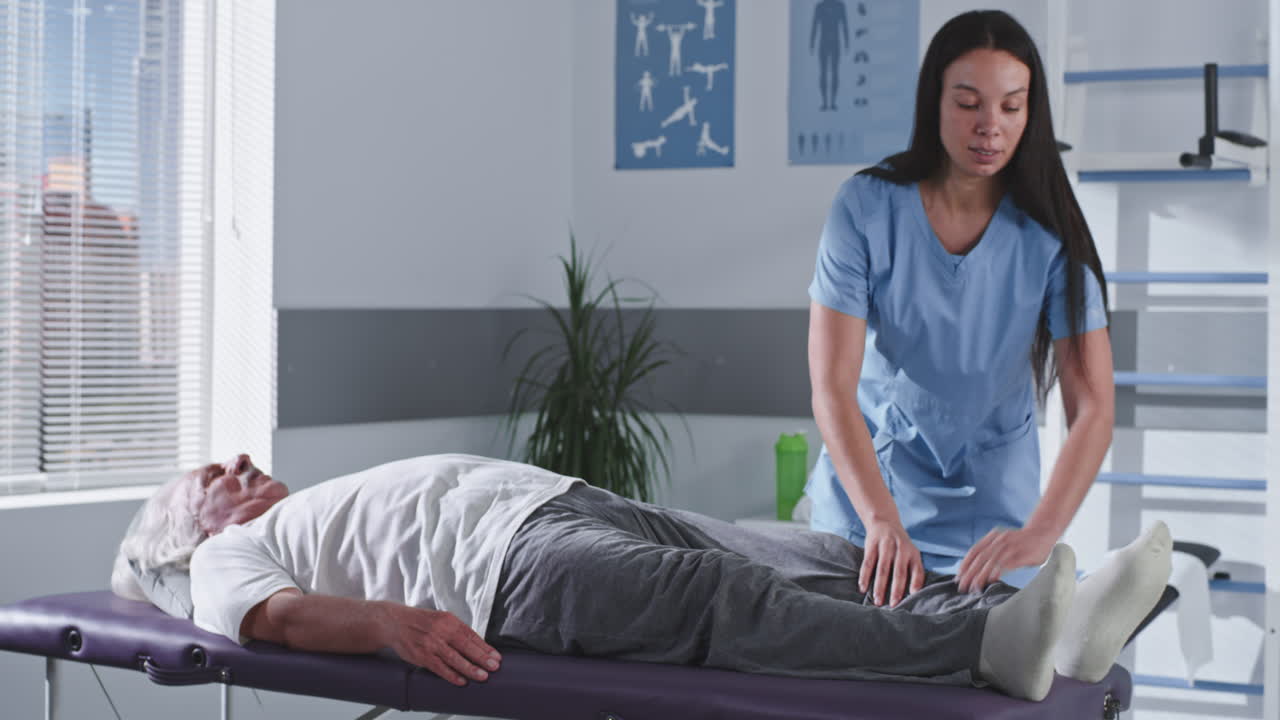 Physical Therapist Assisting Elderly Patient with Knee Stretching Exercise