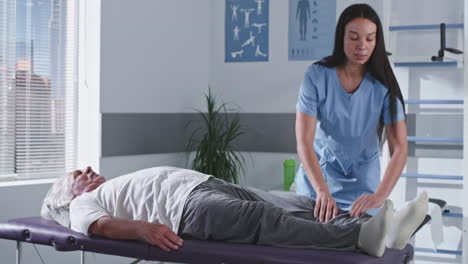 physical therapist assisting elderly patient with knee stretching exercise