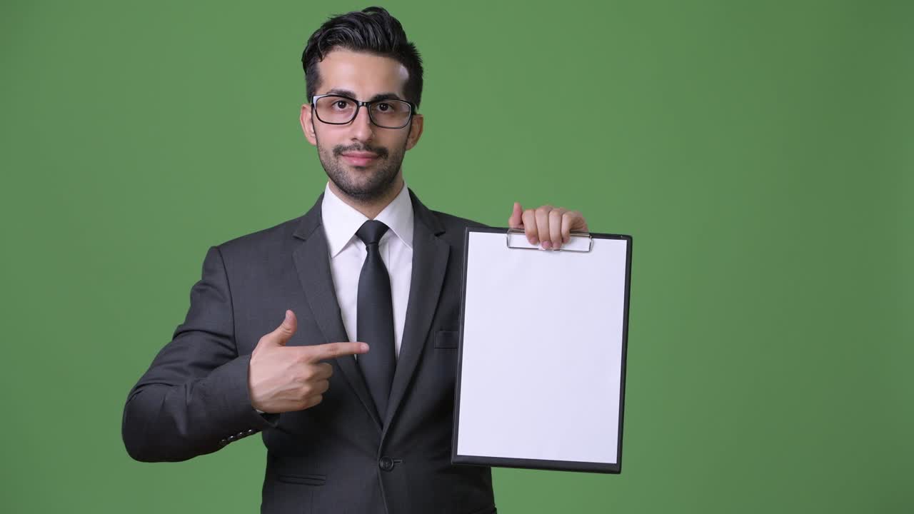 joven empresario persa barbudo y guapo contra un fondo verde