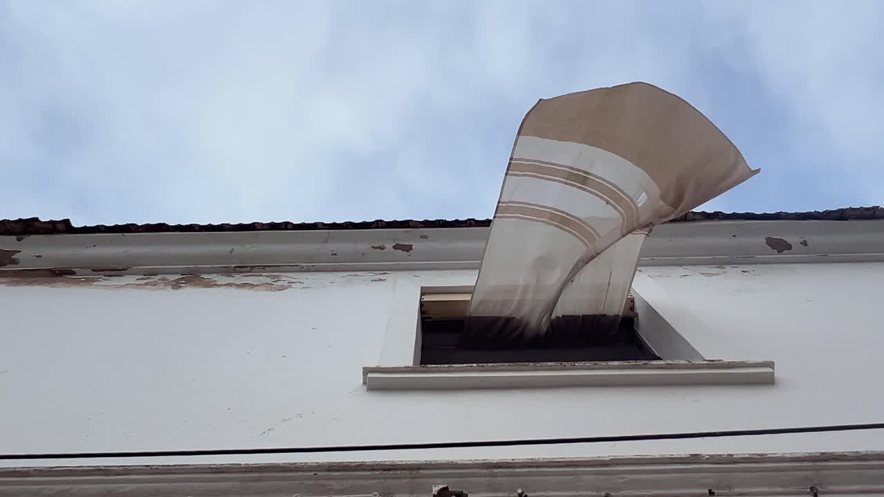 view from below, the wind pulls the curtain out of the house