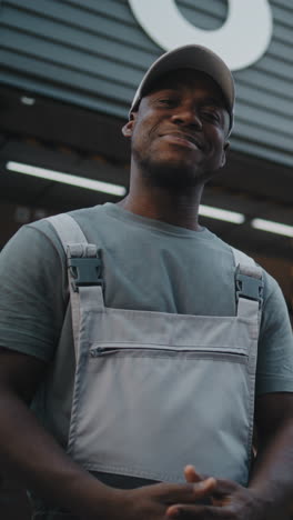 a black delivery worker in uniform handles a package and smiles, depicting professional service