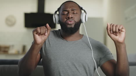 happy man singing in headphones at kitchen