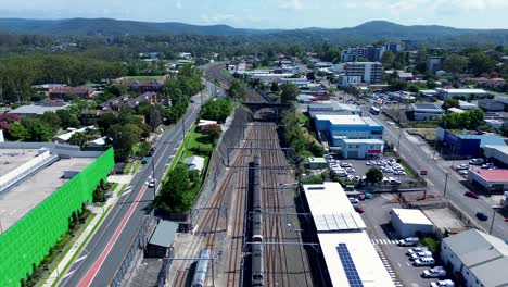 drone aerial view train leaving station platform railway track line gosford city buildings architecture cbd transportation travel narara wyoming australia 4k