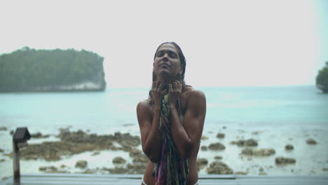 woman in bikini drying off in the rain on a tropical beach