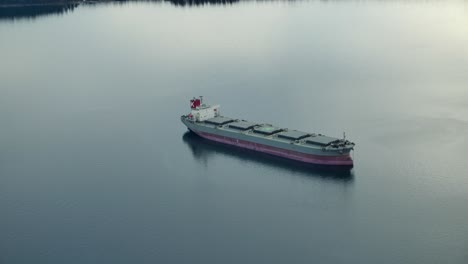 Tranquil-View-Of-A-Bulk-Carrier-Navigating-In-Waterways-During-Sunrise