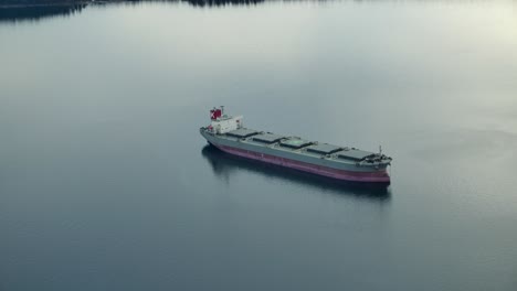 tranquil view of a bulk carrier navigating in waterways during sunrise