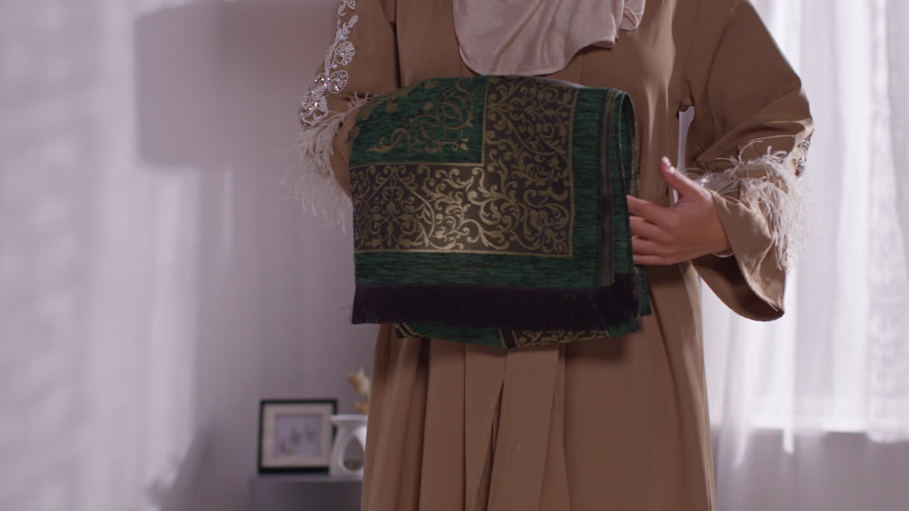 집에서 무슬림 여성이 2층에 기도 매트를 놓고 있습니다.