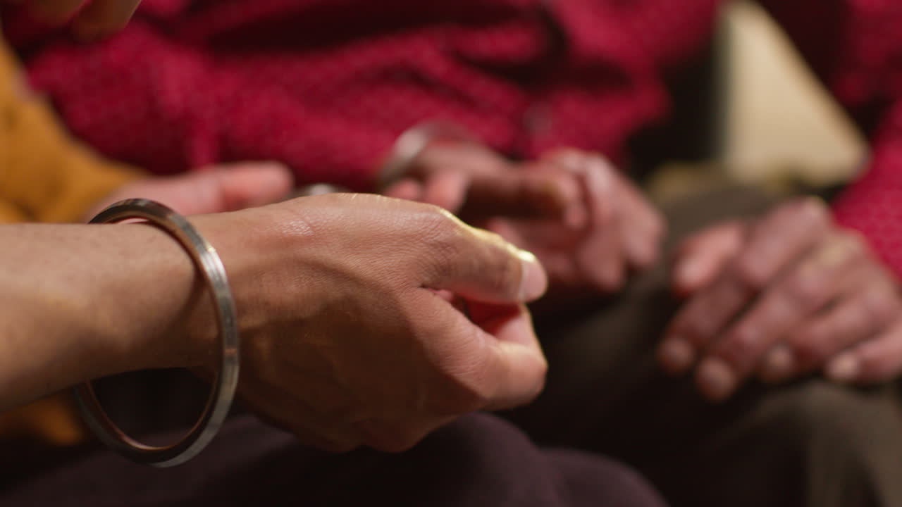 Close Up Of Multi Generation Male Sikh Family Wearing And Discussing Traditional Silver Bangles Or Bracelets Sitting On Sofa At Home 1