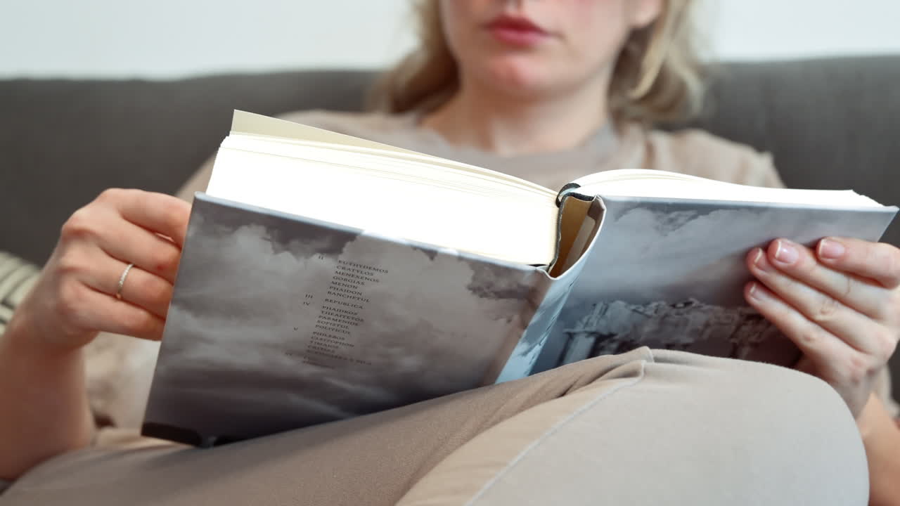 Close up of a woman reading a book at on the couch at home