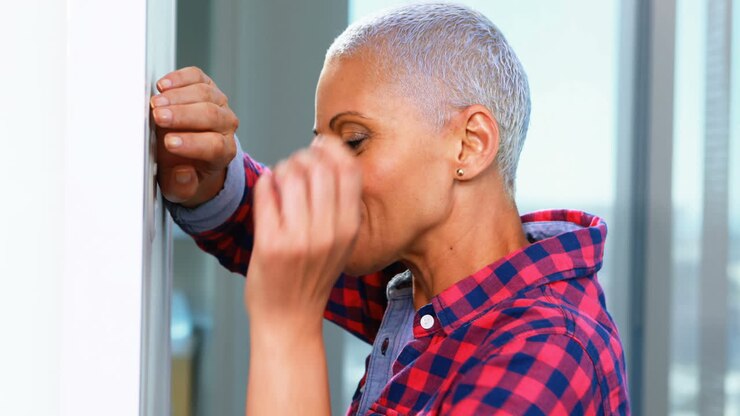 Sad female executive leaning on wall