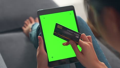 woman holding digital tablet with green screen and mock up credit card with paying for shopping online, chromakey screen for advertising.