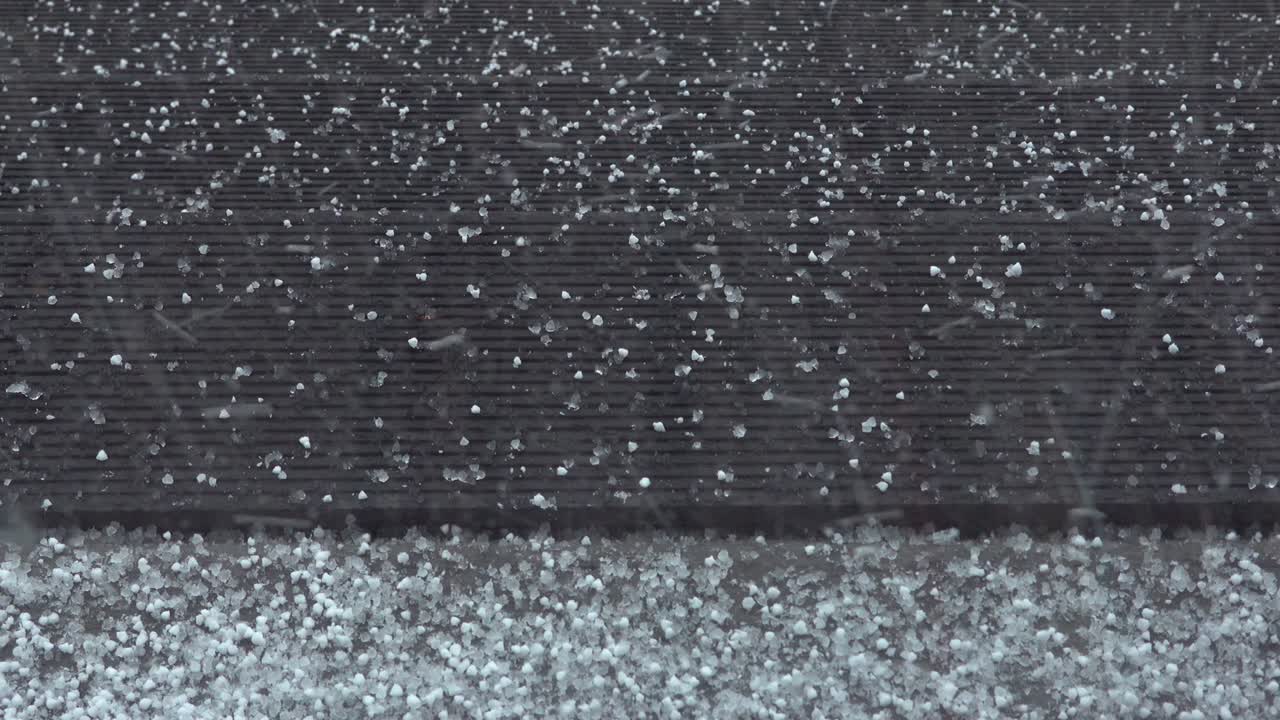 Unexpected hail storm in a stormy spring day. Close up of large ice pieces falling from the sky on the porch