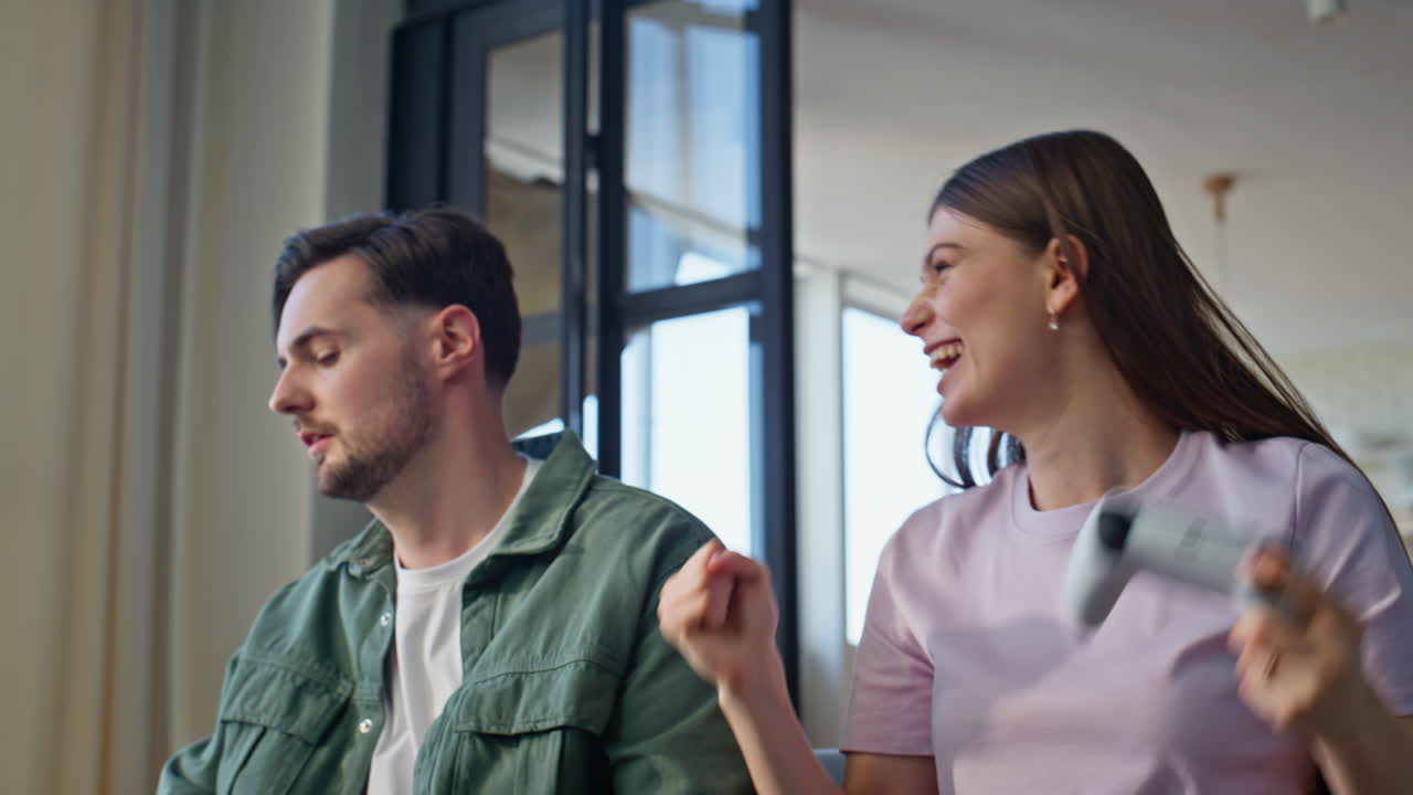 Friends hands holding joysticks playing video game at home closeup. Woman winner