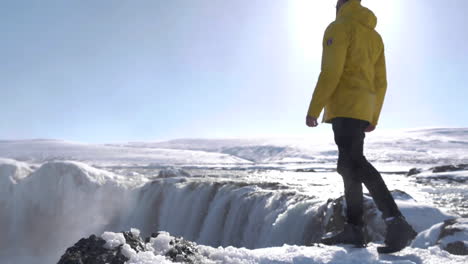 young male traveler in front of beautiful godafoss waterfall in winter