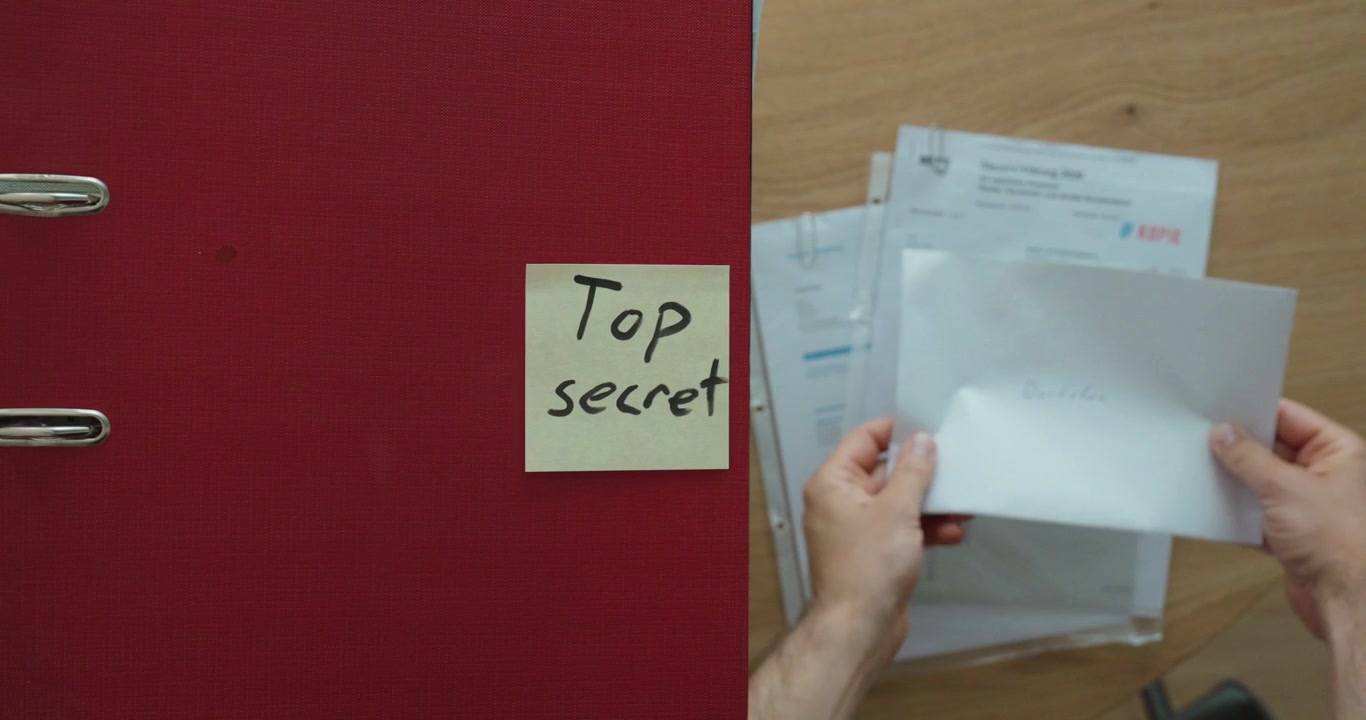 Una persona esamina documenti accanto a una cartella etichettata "Top Secret", che rappresenta informazioni riservate, documenti classificati e gestione sicura dei documenti