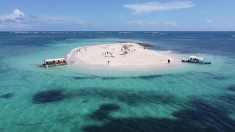 vacationers and tour boats on tiny sandbank of naked island in siargao, aerial