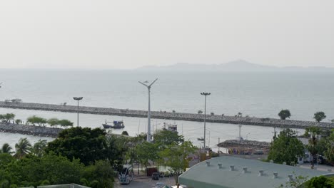 a scenic view of a fishing boat and wind turbines at a tranquil seaside harbor.