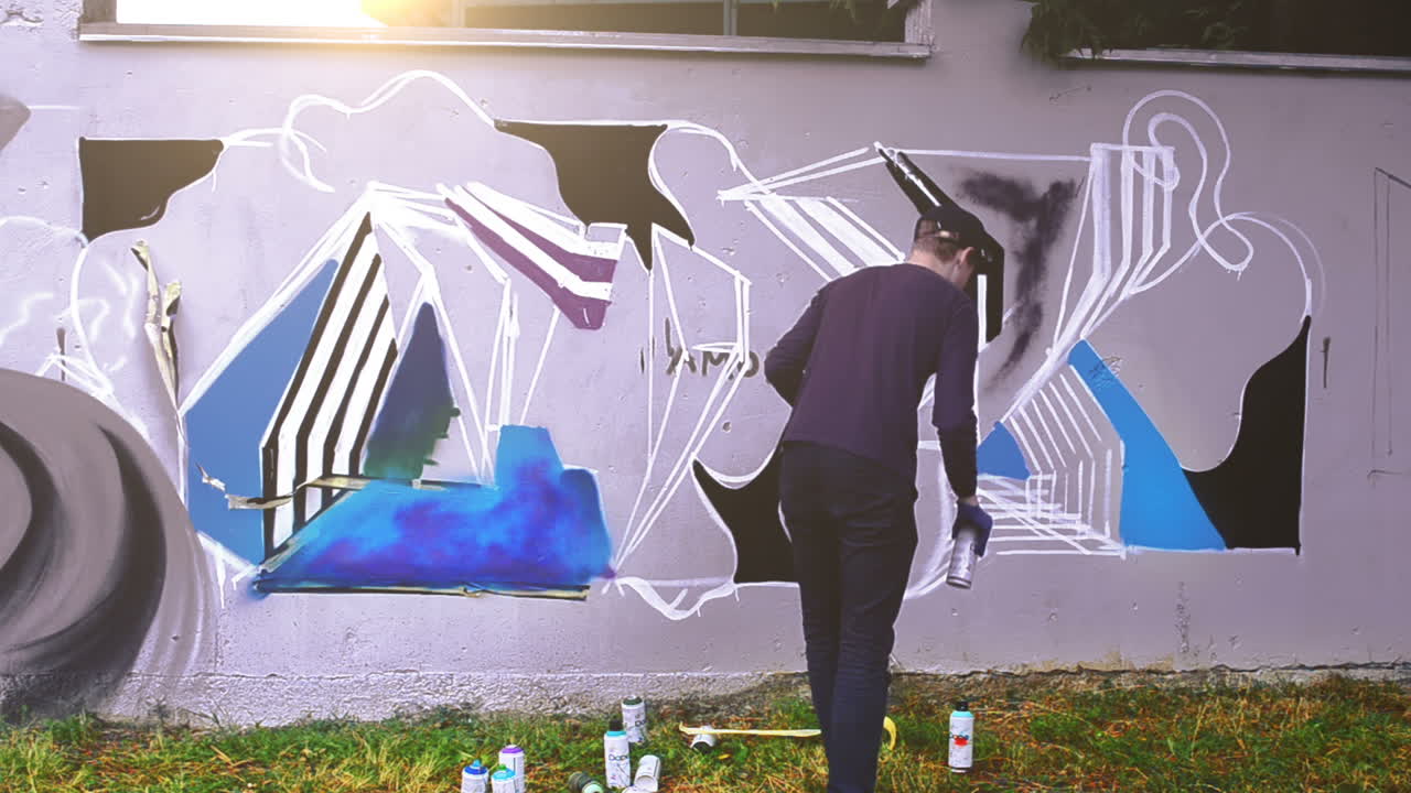 El artista dibuja grafitis en una valla. Grafiti en una valla.