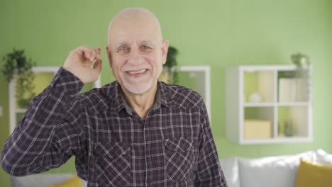 Happy-old-man-dancing-at-home-having-fun-looking-at-camera.