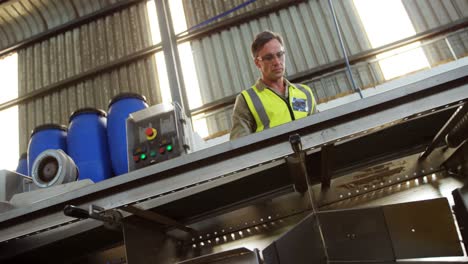 Worker-inspecting-olive-in-machine-in-factory