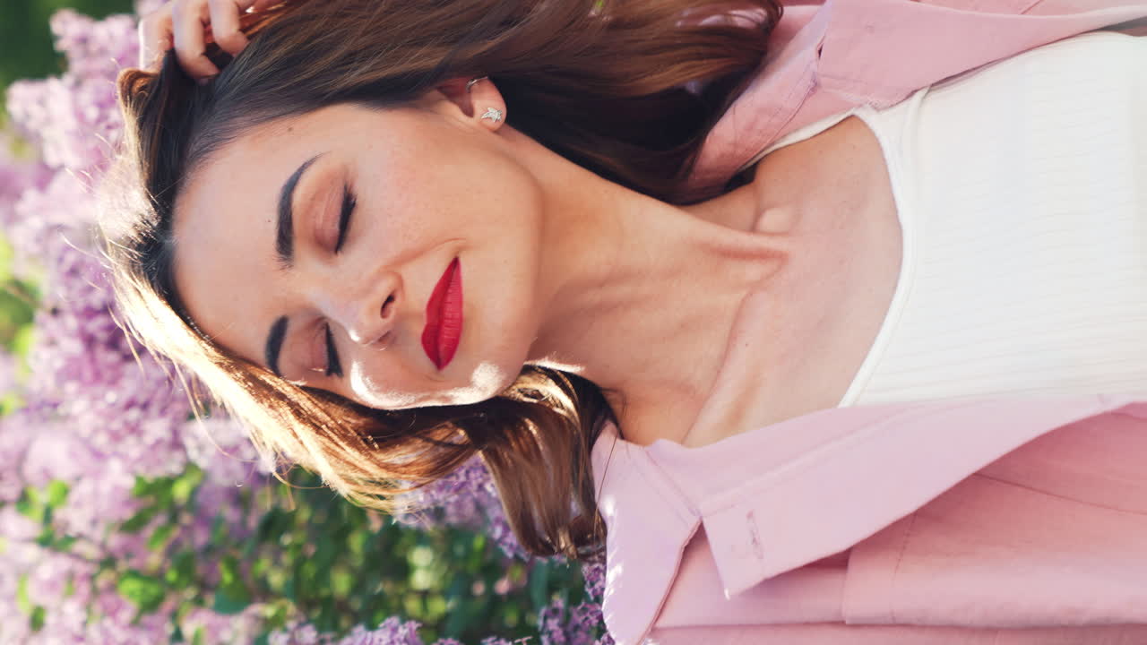 Donna in giacca rosa, circondata da lillà
