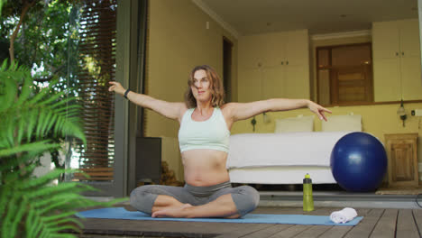 relaxed caucasian pregnant woman practicing yoga on mat at home