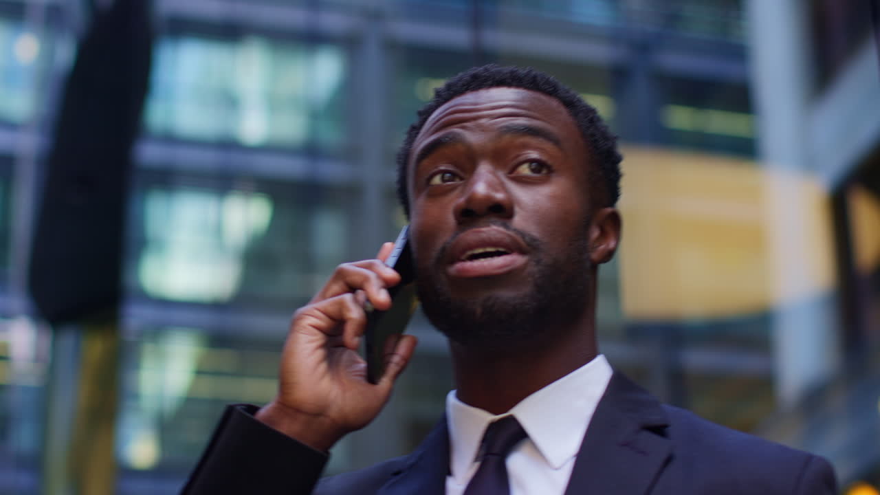 Smiling Young Businessman Wearing Suit Talking On Mobile Phone Standing Outside Offices In The Financial District Of The City Of London UK Shot In Real Time