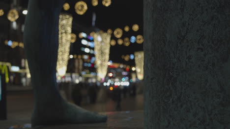 statue foot and blurred background of street decorated with christmas lights