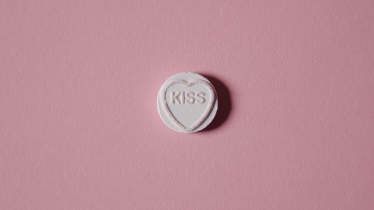 분홍색 배경에 단어 키스와 함께 심장 사탕을 손에 들고