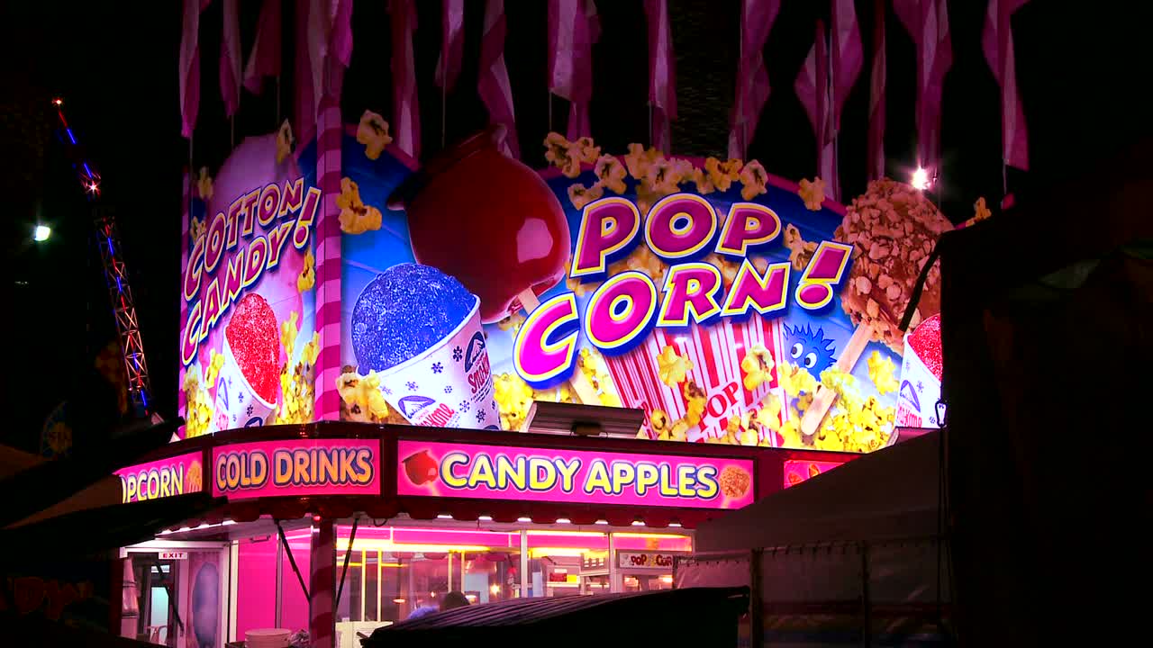 밤에 놀이공원 카니발이나 주 박람회에서 팝콘과 사탕 사과를 제공하는 포장마차의 설정 샷