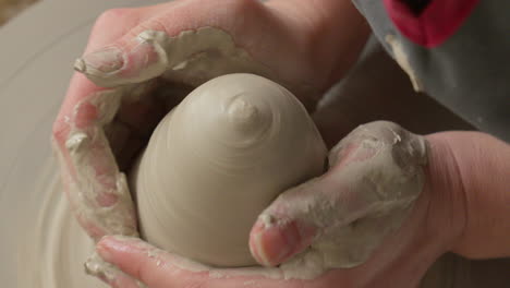 ceramics artist centers clay on a pottery wheel with both hands